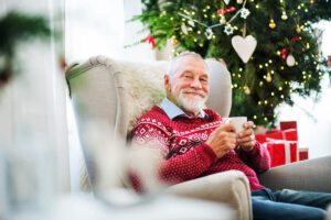 The Craig | Happy senior sitting in a chair by the holiday tree