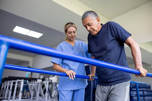 A senior man doing physical therapy with a nurse