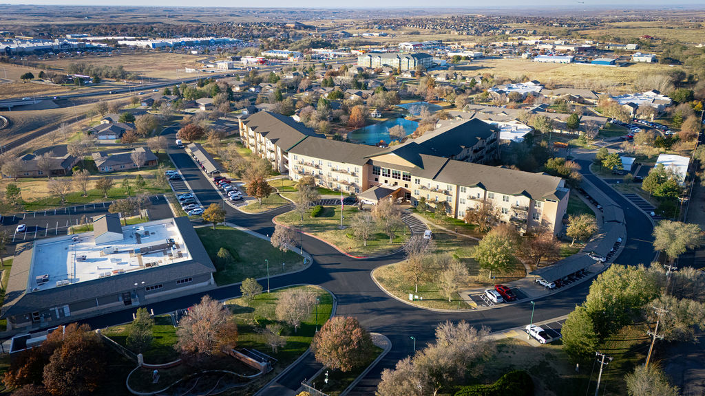 Aerial view of suburban area with buildings, roads, and trees on sunny day.